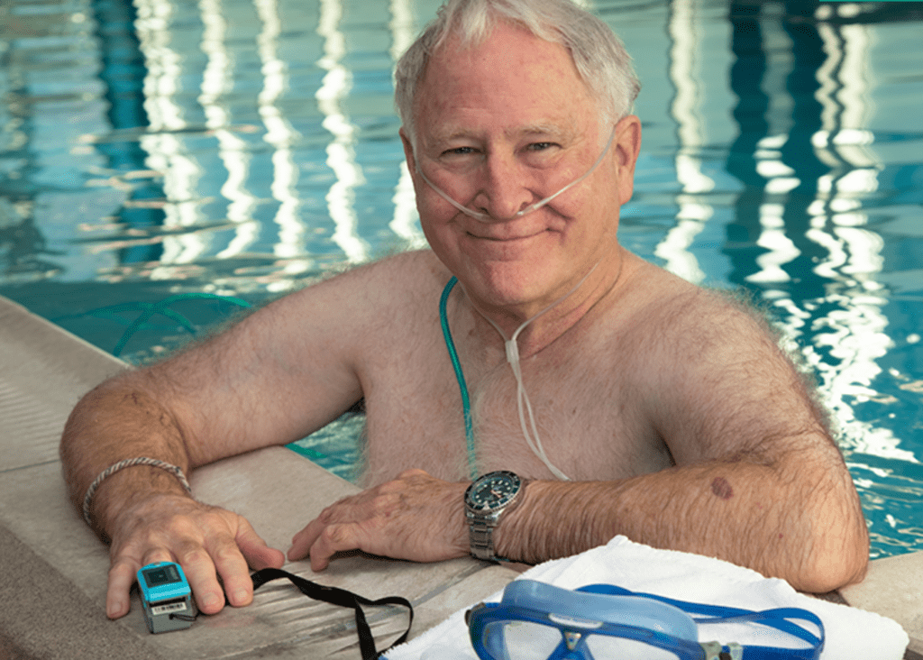 Man at edge of swimming pool with pulse oximeter