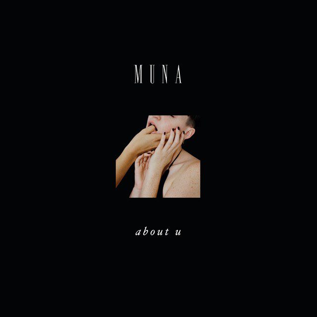 MUNA album art for 'About You' with a large black background with a small image of a woman with another persons thumb in her mouth.