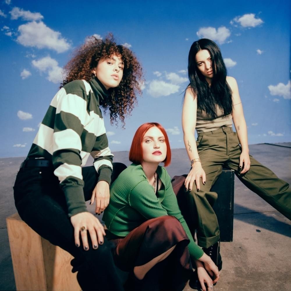 MUNA album art for 'Saves the World' with three female presenting adults posing outside in a desert.